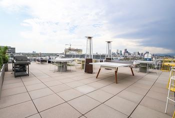 A rooftop patio with a table and chairs overlooking a city skyline. at RiDE at RiNo Apartments, Denver, CO, 80216